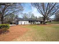Charming white brick ranch-style home featuring a well-maintained lawn and mature trees on a sunny day at 1199 Murray Sw Cir, Marietta, GA 30064