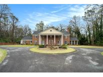 Stately brick home featuring a circular driveway and classic architectural details with large columns at 3074 Cascade Sw Rd, Atlanta, GA 30311