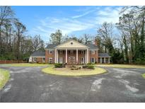 Stately brick home featuring a circular driveway, manicured lawn, and classic colonial design at 3074 Cascade Sw Rd, Atlanta, GA 30311