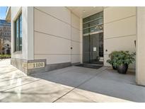 Condo building entrance with glass doors, address signage, and decorative plants at 1100 Howell Mill Nw Rd # 613, Atlanta, GA 30318