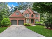 Charming two-story brick home with a well-manicured lawn and mature trees, offering great curb appeal and a welcoming ambiance at 5425 Edinbourgh Ct, Cumming, GA 30040