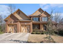 Charming brick home showcasing a three-car garage, complemented by manicured landscaping and a welcoming facade at 117 Olde Heritage Way, Woodstock, GA 30188