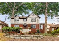 Charming two-story home with a brick and stucco exterior, set amidst mature trees and a landscaped front yard at 591 E Morningside Ne Dr, Atlanta, GA 30324