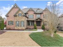 Beautiful two-story brick home featuring manicured landscaping, stone accents, and an elegant entrance at 6040 Boulder Bluff Dr, Cumming, GA 30040