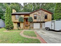 Charming home featuring a stone accent exterior, two-car garage and lush green lawn with mature landscaping at 1922 Marshes Glenn Dr, Norcross, GA 30071