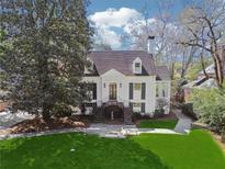 Charming white home with lush front lawn, mature trees, and a welcoming staircase entrance at 890 W Wesley Nw Rd, Atlanta, GA 30327