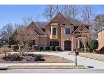 Elegant brick home boasts a manicured lawn and a welcoming driveway, complemented by a stylish front entry at 1540 Turtle Pond Dr, Hoschton, GA 30548