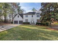 Charming two-story white home with a well-manicured front lawn and mature trees, creating a welcoming curb appeal at 3471 Greyfield Nw Ln, Kennesaw, GA 30152