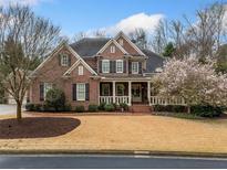 Beautiful brick home featuring a manicured lawn, black shutters, and a charming front porch at 3821 Teesdale Ct, Atlanta, GA 30350