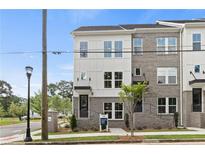 Modern townhome featuring gray brick, white siding, large windows, and a stylish black front door at 2567 Astaire Ct, Atlanta, GA 30318