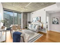 Bright living room with floor-to-ceiling windows offering city views and hardwood floors at 855 Peachtree Ne St # 1906, Atlanta, GA 30308