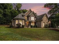 Charming brick home with a well-manicured lawn, mature trees, and architectural details under a pastel sunset at 375 Beracah Tr Sw Trl, Atlanta, GA 30331