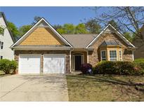 Charming home featuring stone and shingle accents, well-manicured landscaping, and an attached two-car garage at 5250 Fieldgate Ridge Dr, Cumming, GA 30028