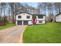 Charming home featuring a red door, a two-car garage, and a well-maintained front lawn at 7012 Winter Woods Ct, Morrow, GA 30260