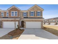 Beautiful brick two-story townhouse featuring a two-car garage and a well-manicured front yard at 935 Elwood St, Dacula, GA 30019