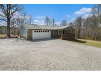 Charming single-story home featuring a stone facade and a spacious driveway leading to an attached two-car garage at 1875 Ebenezer Sw Rd, Conyers, GA 30094