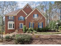 Charming brick home featuring a well-maintained lawn, complemented by tasteful landscaping and beautiful blue shutters at 3872 Windrose Ln, Marietta, GA 30062