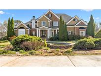 Beautiful two-story home with a water feature, manicured landscaping, and brick and tan siding at 100 Annes Ln, Sharpsburg, GA 30277
