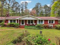 Charming red brick home with a well-manicured front lawn and blossoming azalea bushes at 738 Lauren Cir, Lawrenceville, GA 30043