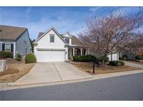 Charming two-story home featuring a well-manicured lawn, a two car garage, and a blooming tree at 1555 Diplomat Dr, Cumming, GA 30041