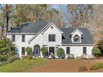 Charming two-story home with a manicured lawn, mature trees, and striking architectural details at 8505 Haven Wood Trl, Roswell, GA 30076