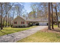 Charming ranch-style home with a well-maintained lawn, mature trees, and a long driveway leading to an attached garage at 2073 Lou Ct, Grayson, GA 30017