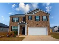 Two-story brick home featuring an attached two-car garage and manicured landscaping at 443 Faulkner St, Stockbridge, GA 30281