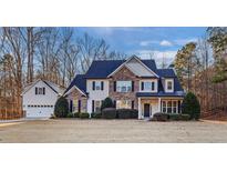 Stunning two-story home features a stone facade, a dark blue roof, manicured shrubs, and an attached three-car garage at 310 Persimmon Dr, Sharpsburg, GA 30277