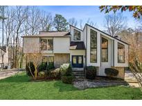Contemporary two-story home with stone accents, a manicured lawn, and unique architectural details at 2724 Long Lake Ne Dr, Roswell, GA 30075