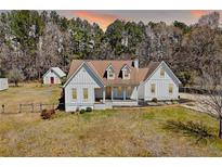 Charming farmhouse-style home featuring a white exterior, dormer windows, and a welcoming front porch at 1479 New Hope Rd, Locust Grove, GA 30248