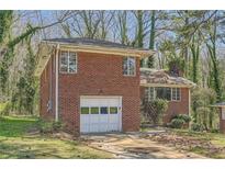 Charming brick home featuring an attached garage and mature trees in a serene setting at 195 Hermer Nw Cir, Atlanta, GA 30311