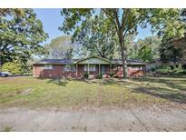 Charming brick ranch home with a well-maintained lawn and mature trees providing shade at 1189 E East Fayetteville Rd, Riverdale, GA 30296
