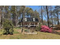 Charming two-story home featuring a front porch, inviting landscaping, and a yard filled with mature trees at 705 Mill Creek Rdg, Woodstock, GA 30188