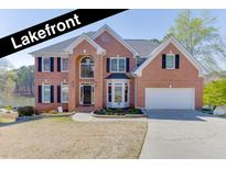 Stunning two-story brick home with lakefront views, black shutters, and a well-manicured lawn at 335 Lake Bluff Ct, Suwanee, GA 30024