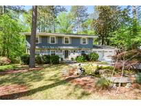Charming two-story home with a stone facade, manicured landscaping, and a tranquil pond at 4400 Huntington Cir, Dunwoody, GA 30338