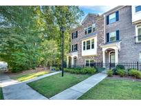 Charming brick townhome with manicured front lawn and black wrought iron fence at 1007 Belle Ave, Roswell, GA 30076