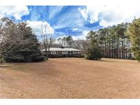 A ranch-style brick home with a well-manicured lawn and mature trees against a beautiful blue sky at 2443 Highway 92 S, Fayetteville, GA 30215