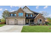 Inviting two-story home featuring a brick facade, manicured lawn, and a spacious three-car garage at 1301 Odell Ct, Hoschton, GA 30548