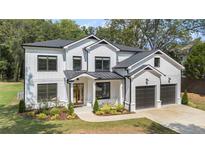 Charming two-story home with white siding, black trim, a 2-car garage, and professional landscaping at 396 Academy St, Alpharetta, GA 30009