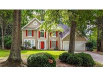 Charming two-story home with red shutters and a well-manicured lawn and mature trees at 7045 Threadstone Overlook, Johns Creek, GA 30097