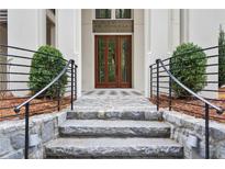 Stone steps lead to a welcoming front entrance with a black iron railing and symmetrical landscaping at 98 Sheridan Dr, Atlanta, GA 30305
