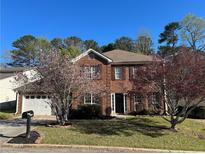 Charming two-story brick home featuring a well-manicured lawn and mature flowering trees at 5942 King Way Walk, Lithonia, GA 30058