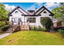Charming two-story home with white painted brick, dark trim, landscaped yard, and stone accent wall at 1448 N Highland Ne Ave, Atlanta, GA 30306