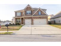 Two-story brick and stone home with a three car garage and concrete driveway at 2875 Bluestone Sw Dr, Atlanta, GA 30331