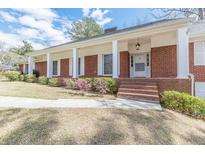 Charming brick home featuring a welcoming front porch with large white columns and shuttered windows at 3390 Somerset Sw Trl, Atlanta, GA 30331
