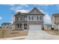 Two story home featuring a two car garage, brick accents, gray siding, and blue shutters at 704 Bristol Dr, Loganville, GA 30052