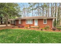 Charming brick home featuring a well-maintained lawn and mature trees at 1334 Jennie Sw Ln, Lilburn, GA 30047