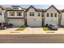 Charming townhomes featuring a white brick facade, two stories, and individual one-car garages at 228 Auburn Valley Way, Auburn, GA 30011