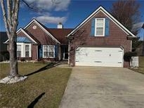 Charming brick home featuring a two-car garage, manicured lawn, and vibrant blue window shutters at 8827 Lake Rd, Union City, GA 30291
