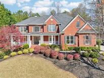 Beautiful red brick home featuring a covered front porch and professionally landscaped front yard at 219 Woodcliff Ct, Suwanee, GA 30024
